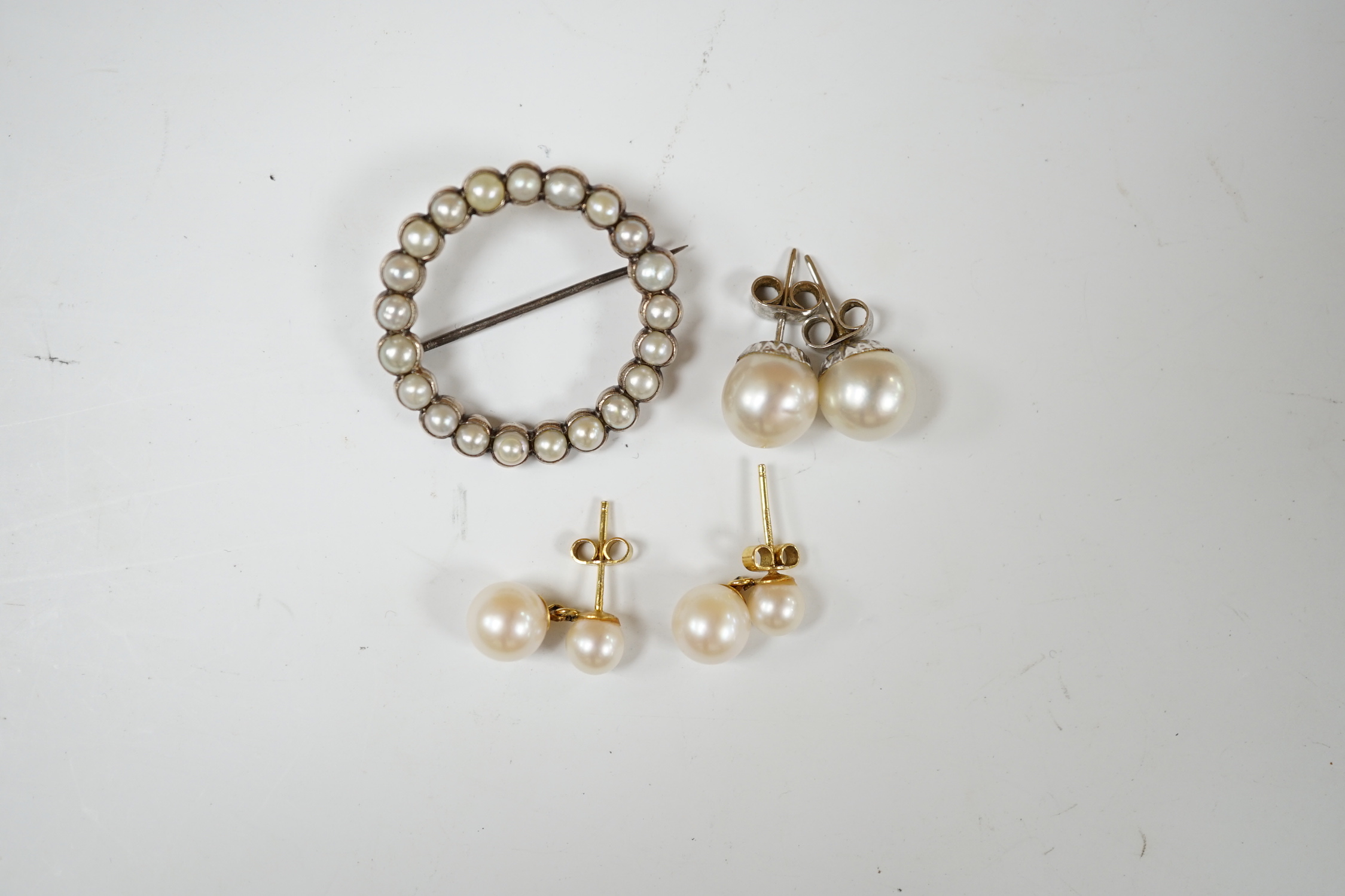 A pair of 9ct gold and two stone cultured pearl set ear studs, one pair of 9ct white metal and single stone cultured pearl set ear studs and a yellow metal and split pearl set open work brooch, 30mm.